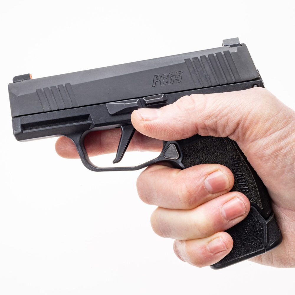 MTX 365 installed onto magazine and into pistol. Shown with hand gripping pistol facing left. Hand has ideal P365 pinky placment